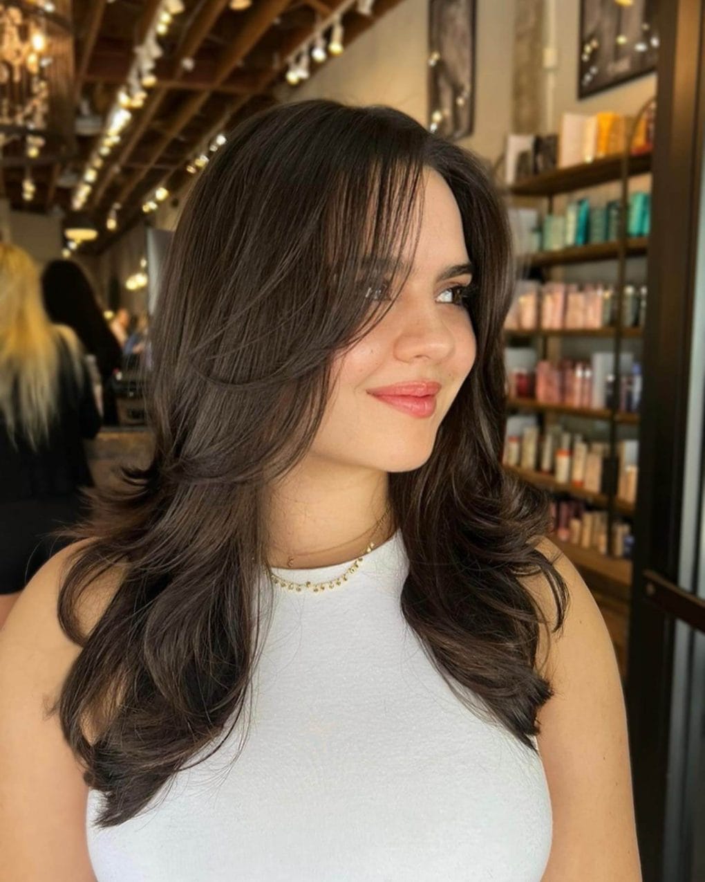 Glossy chestnut waves with modern curtain bangs, exuding elegance and sophistication.