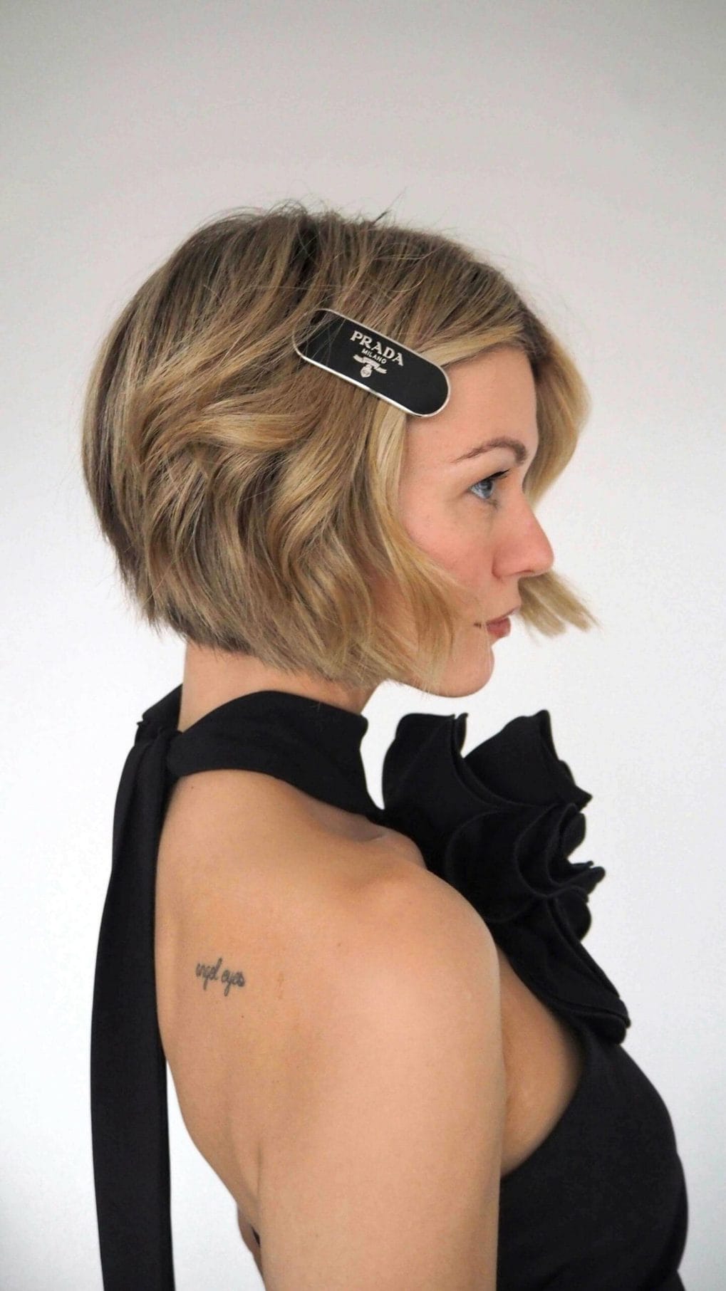 Dynamic blonde bob with natural texture and side-swept bang, accented with a designer clip.