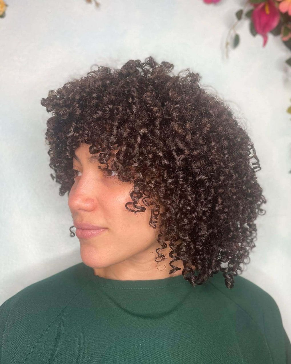 Chic curly cut with defined curls and dark chocolate hue.
