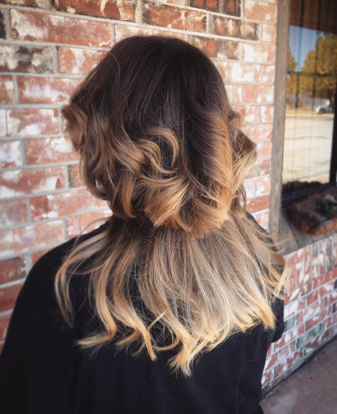 Luxurious jellyfish haircut melding chocolate brown with golden caramel highlights and soft curls.