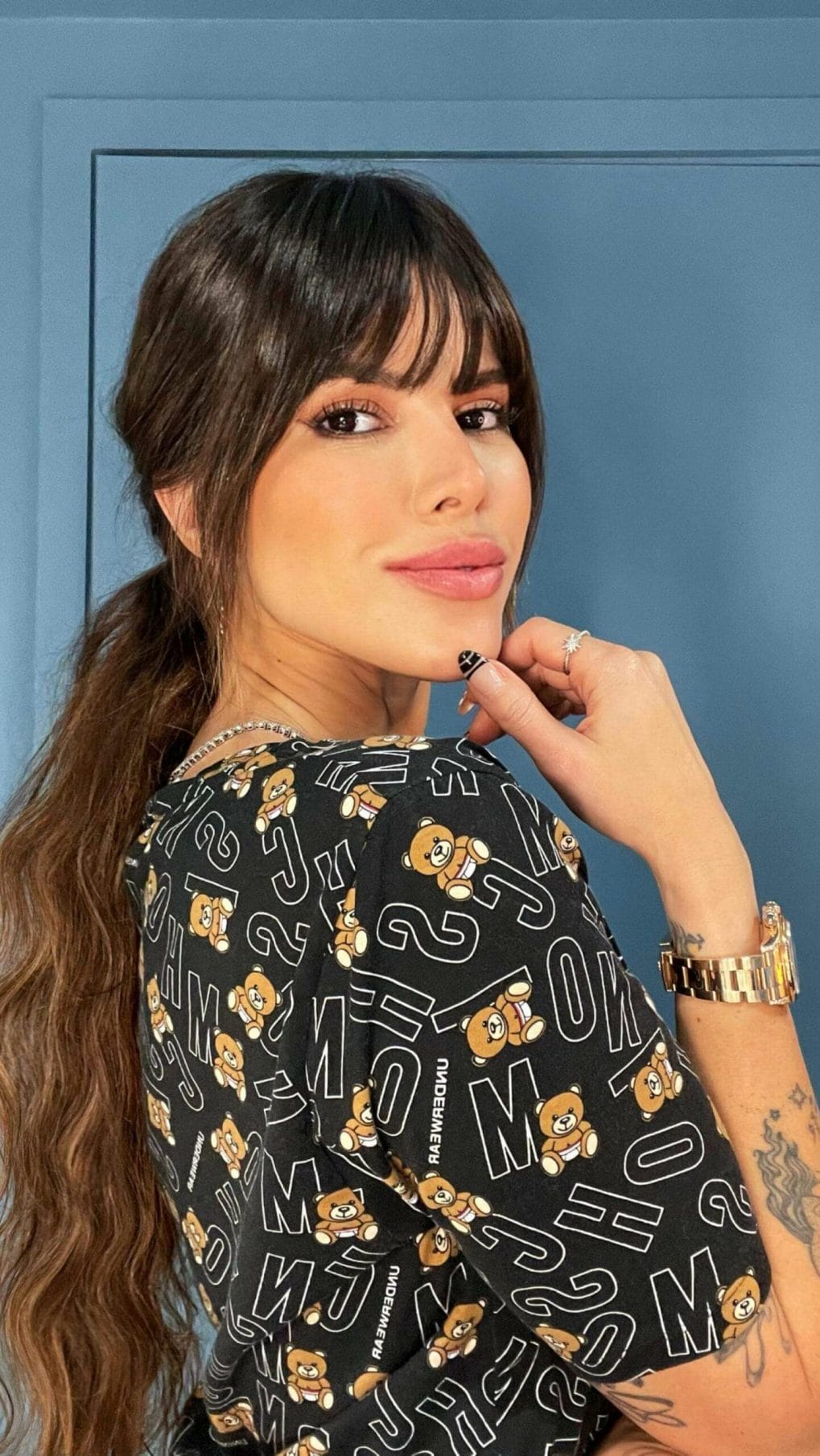 Chocolate-brown wavy ponytail at mid-height, accompanied by playful eyebrow-length bangs for a sophisticated style.