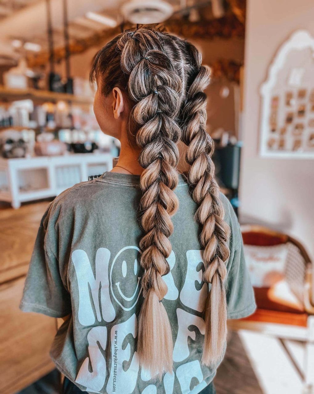 Two chunky, intertwined blonde and brunette braids forming playful ponytails.