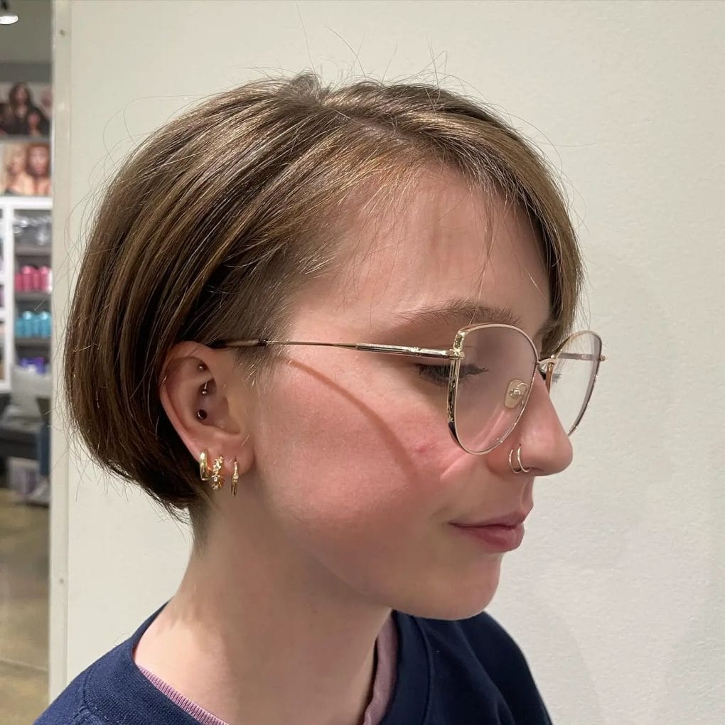 Sleek glasses complementing classic chin-length pixie bob in warm brown