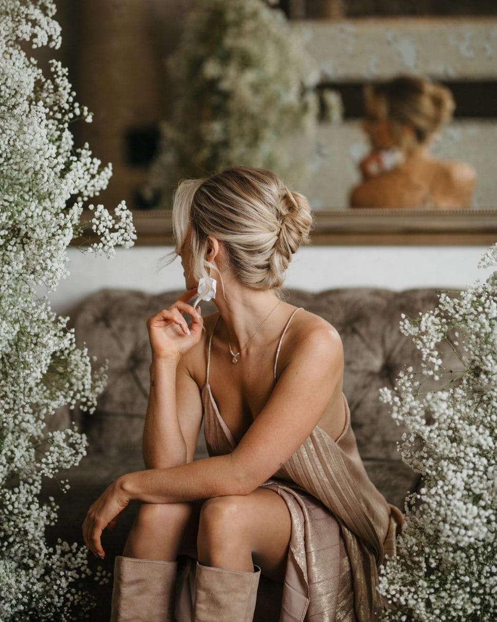 Classic low bun updo with loose strands and a white flower accessory
