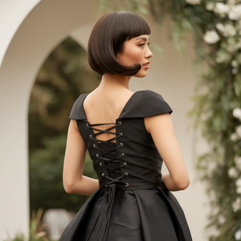 Model showing a Classic French Bob hairstyle with a beautiful black dress.