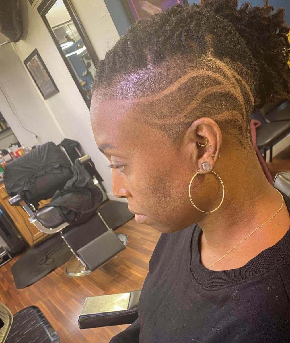 Coiled curls on top with a sweeping undercut featuring organic, wave-like patterns on the sides.
