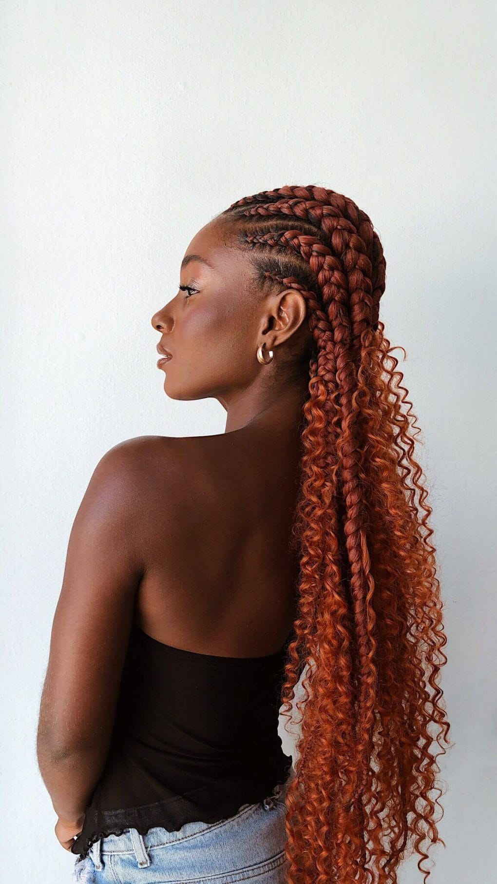 Rich copper tones highlight tight cornrows transitioning into loose curls