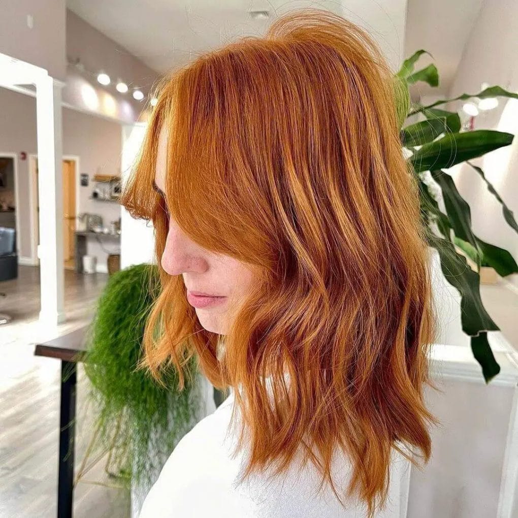 Warm copper mid-length cut with soft, casual curtain bangs.