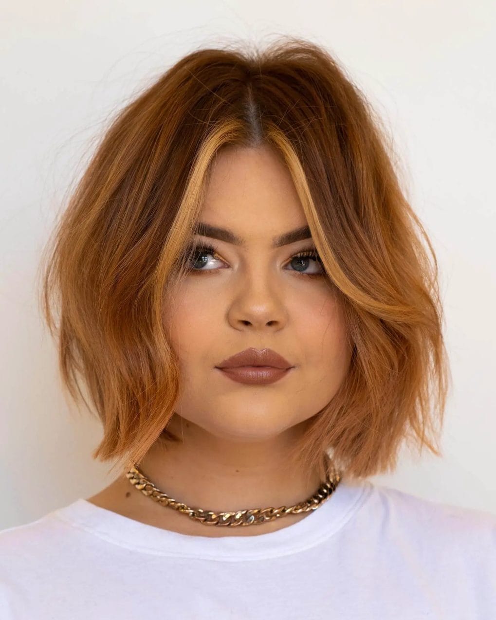 Copper-toned layered bob with straight-across fringe framing the face.