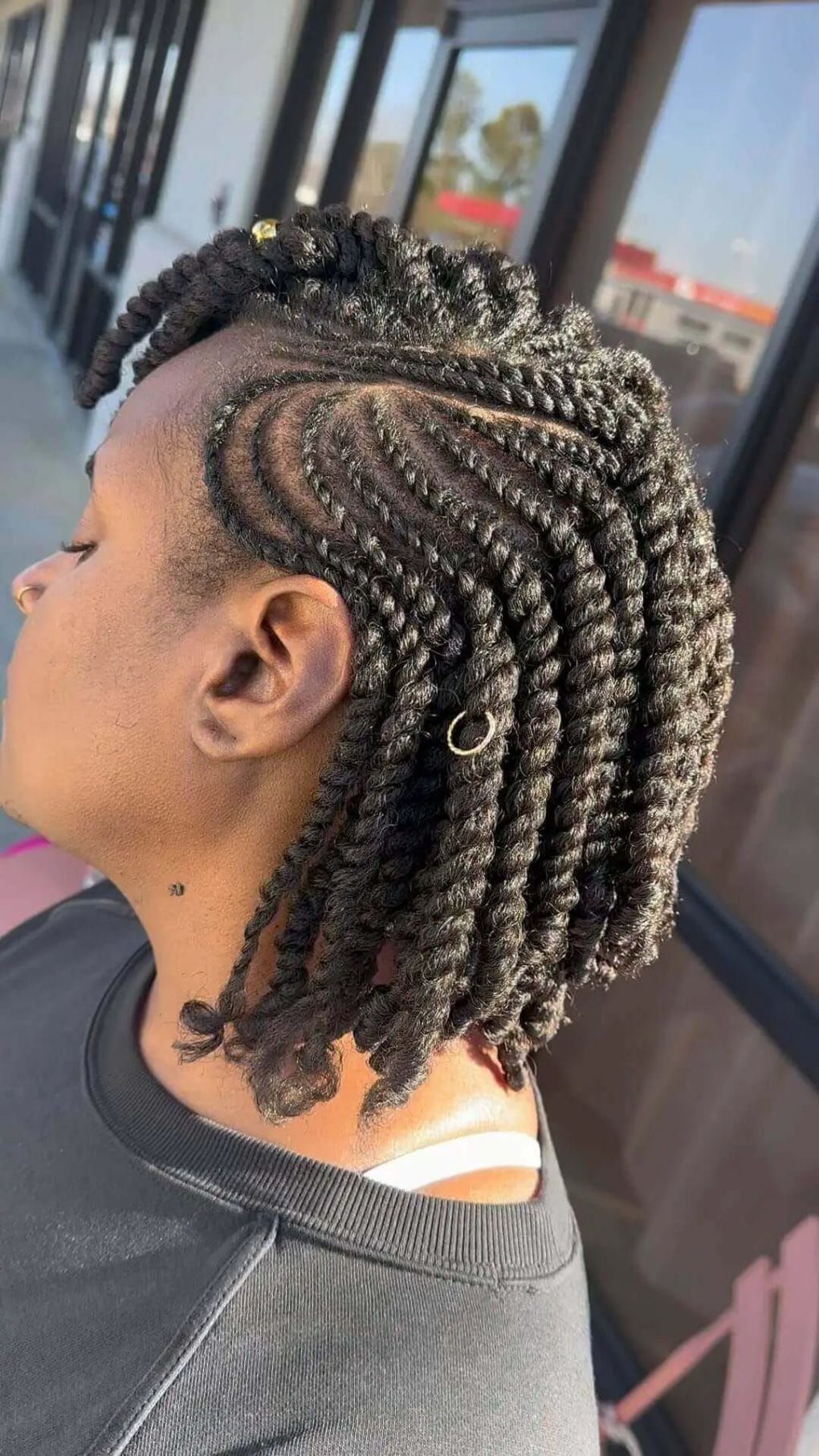 Intricate cornrows spiraling into twists with golden ring accents