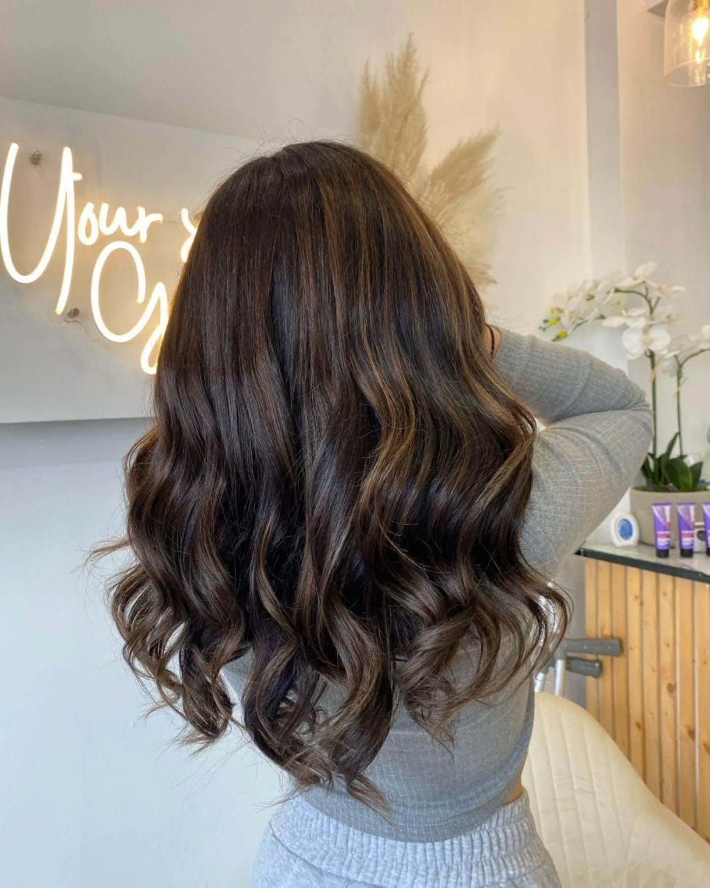 Curls in chocolate to caramel balayage, reflecting a cozy winter evening by the fire.