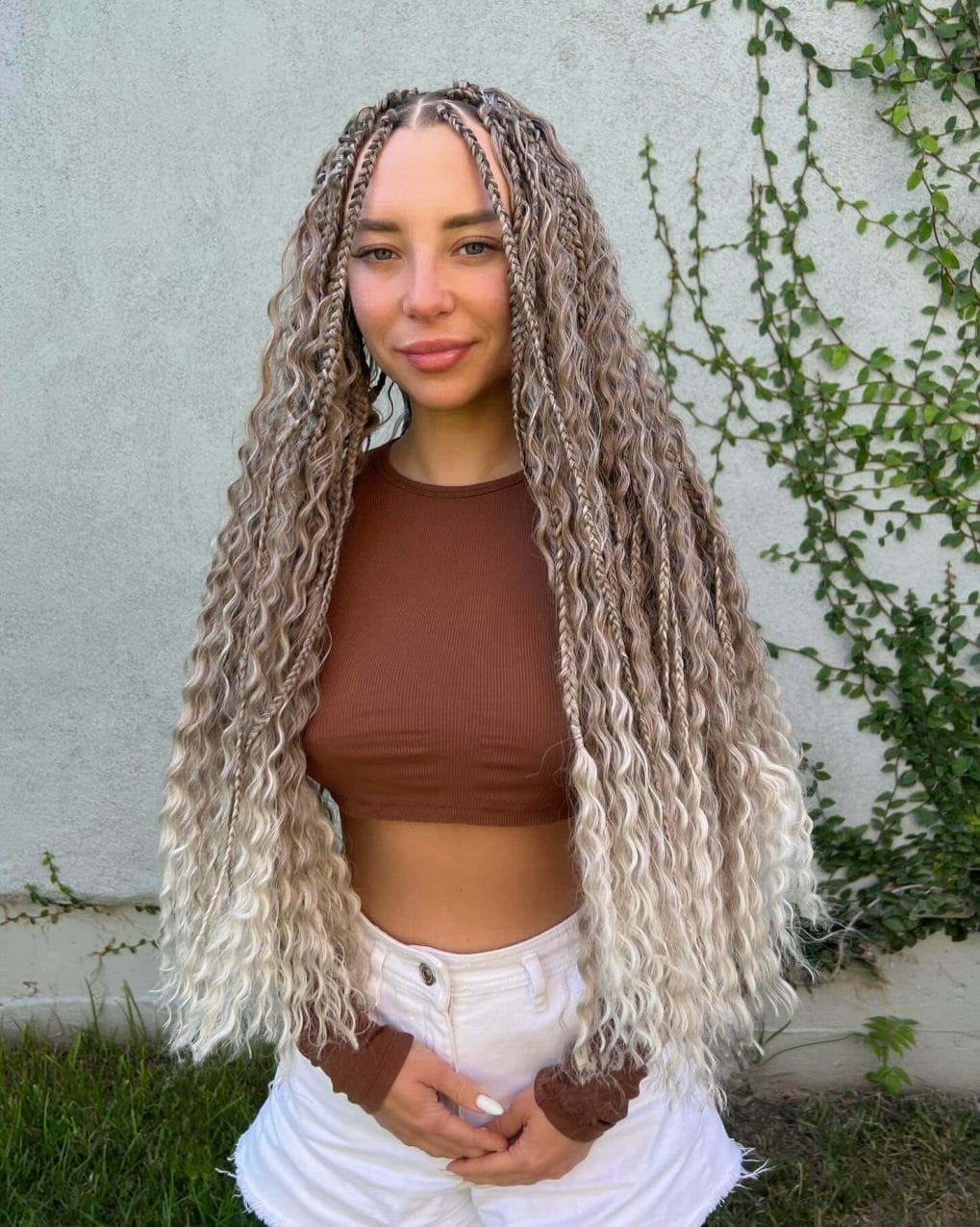 Crimped waves blending from brunette to sun-bleached blonde with small braids, for a laid-back festival look.