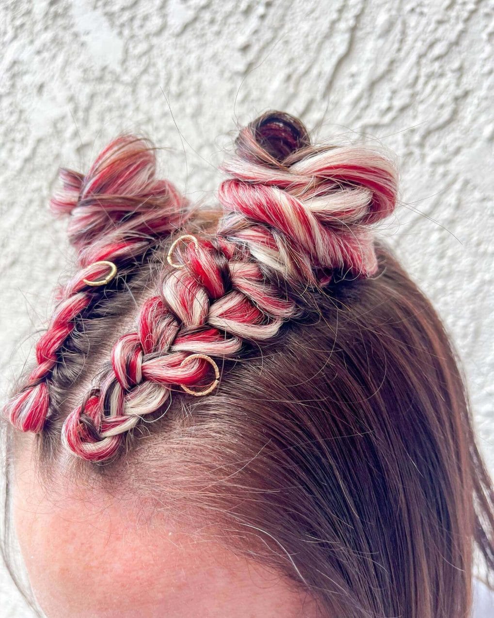 Textured French braid leading to a messy bun with crimson and platinum strands