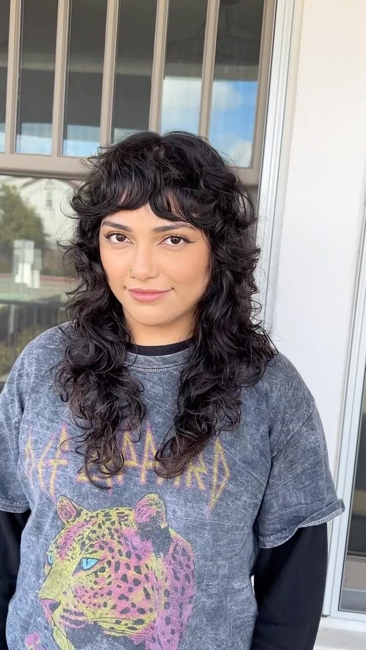 Curly voluminous shaggy mullet with full, richly colored curls framing the face
