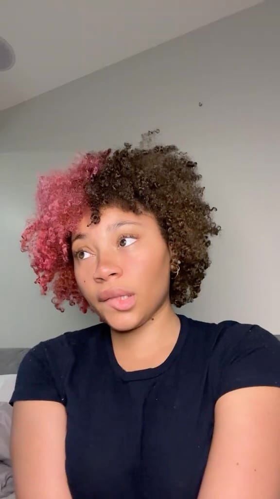 Half-and-half hairstyle merging dark curls with a bold rose tint, blending naturally at the division.