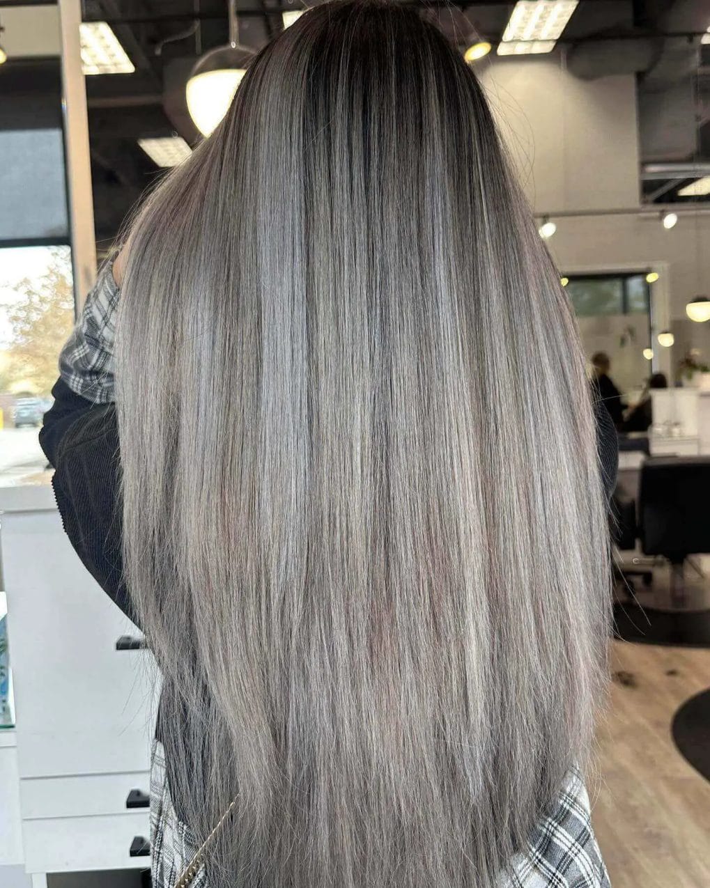 Long straight hair with balayage transition from dark roots to ashy silver.