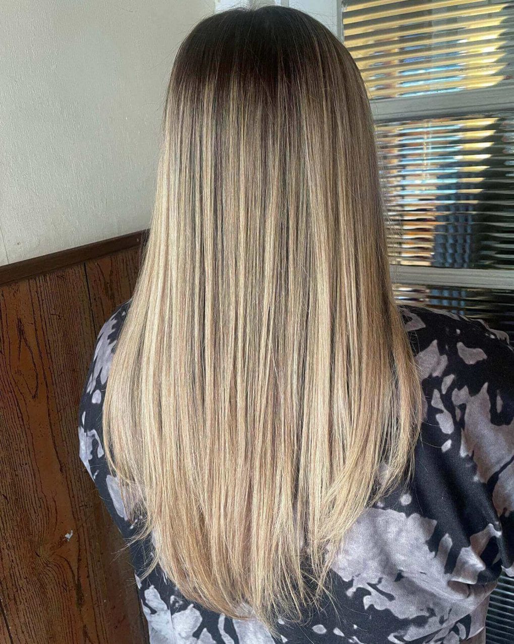 Mid-back length straight hair with dark roots and natural blonde balayage.