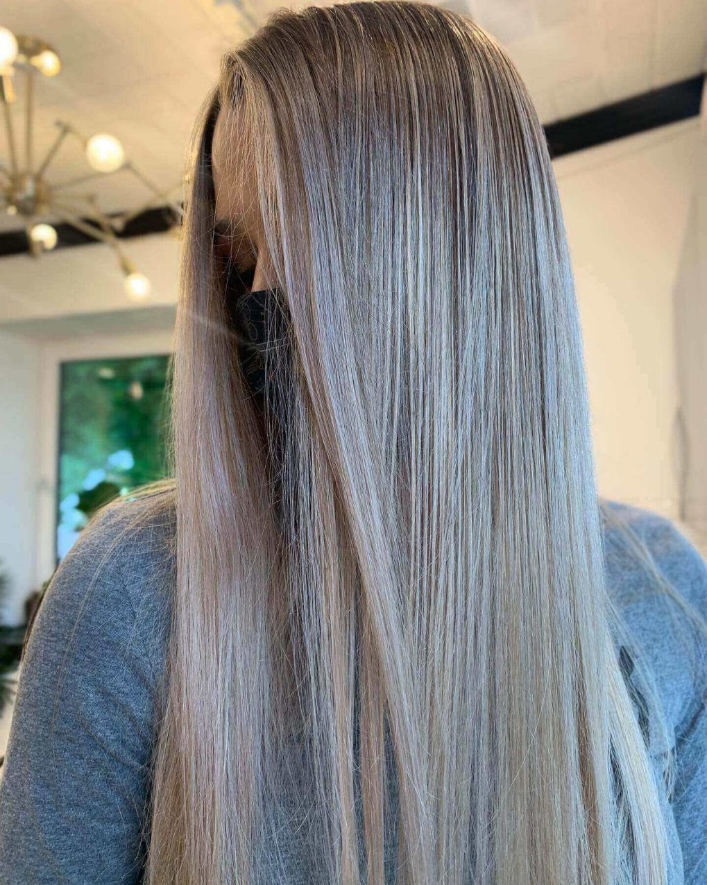 Sleek straight hair with balayage from dark roots to light ethereal ends.