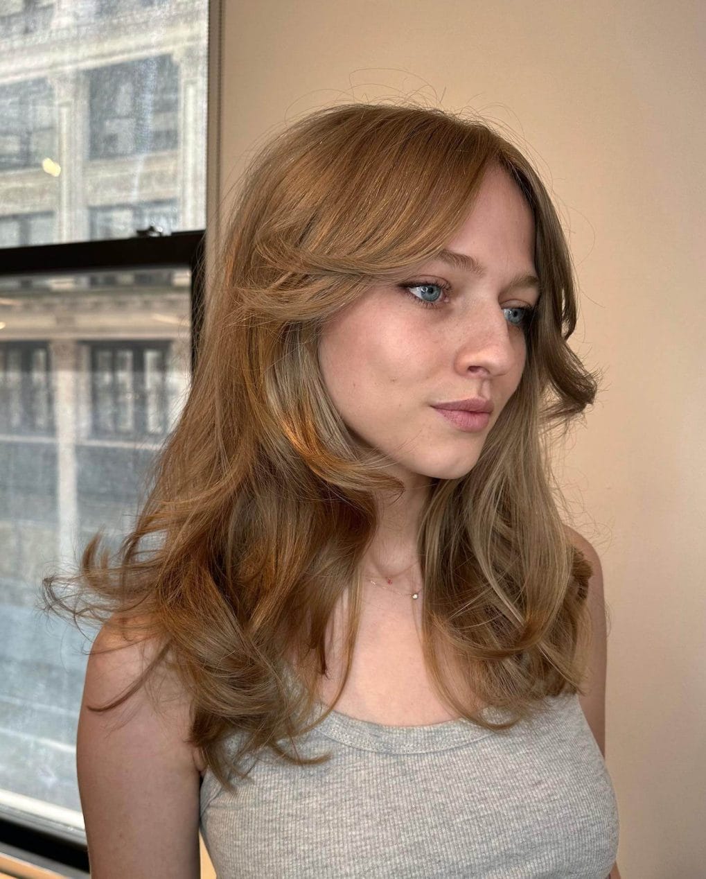 Dark strawberry blonde Butterfly Cut accentuated by short curtain bangs.