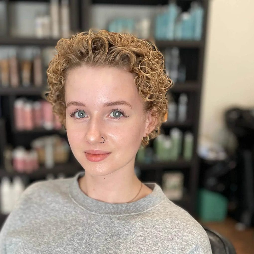 Short, ear-length haircut with tightly coiled, golden curls.