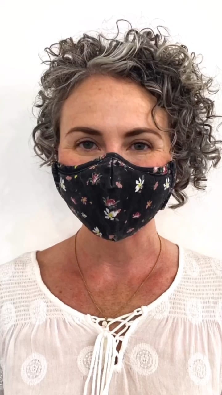 Dignified salt-and-pepper curly pixie beneath floral mask