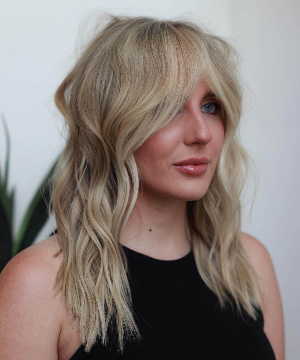 Sun-kissed blonde waves with bardot bangs, exuding a natural, relaxed beachy vibe.