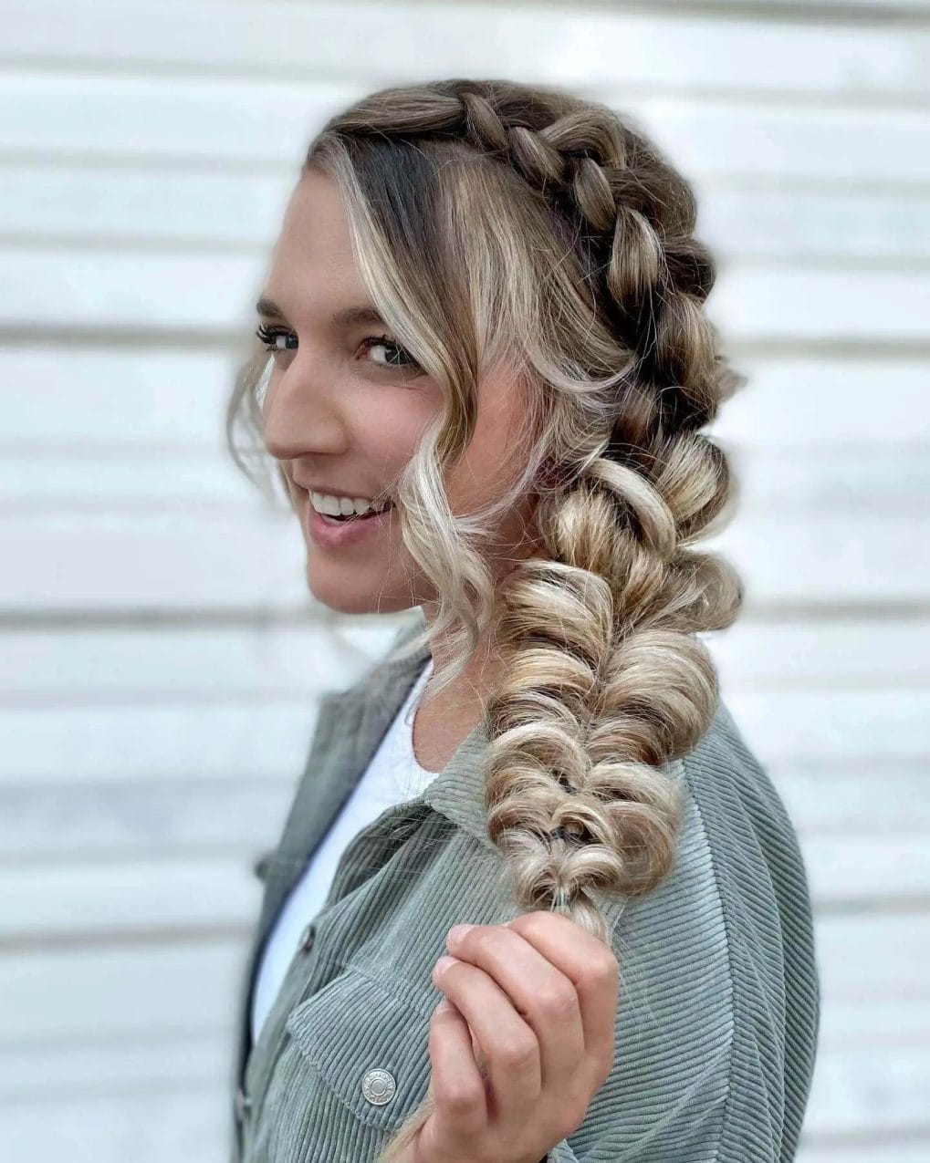 Side Dutch braid transitions into a blonde-highlighted bubble ponytail.