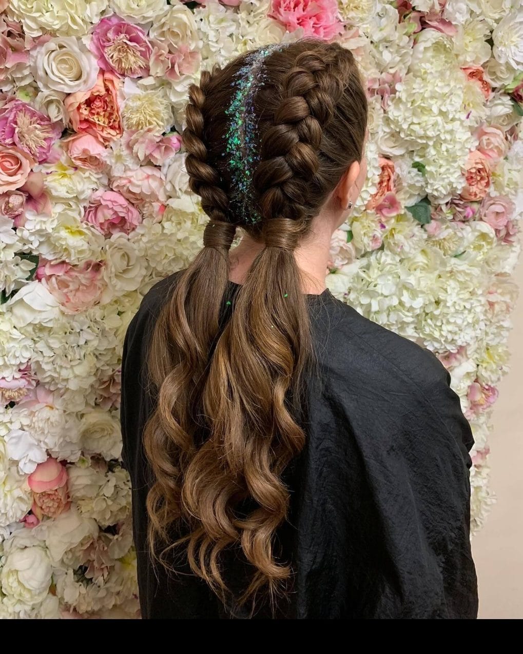 Intricate gymnastics hairstyle with Dutch braids merging into a ponytail, accented by a sparkly stripe