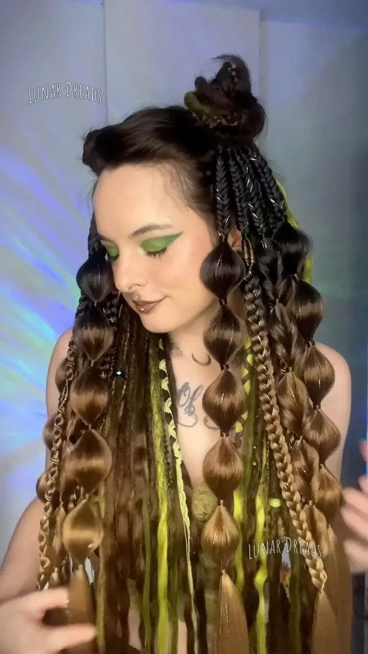 Multi-dimensional braids with earthy tones adorned with green threads.