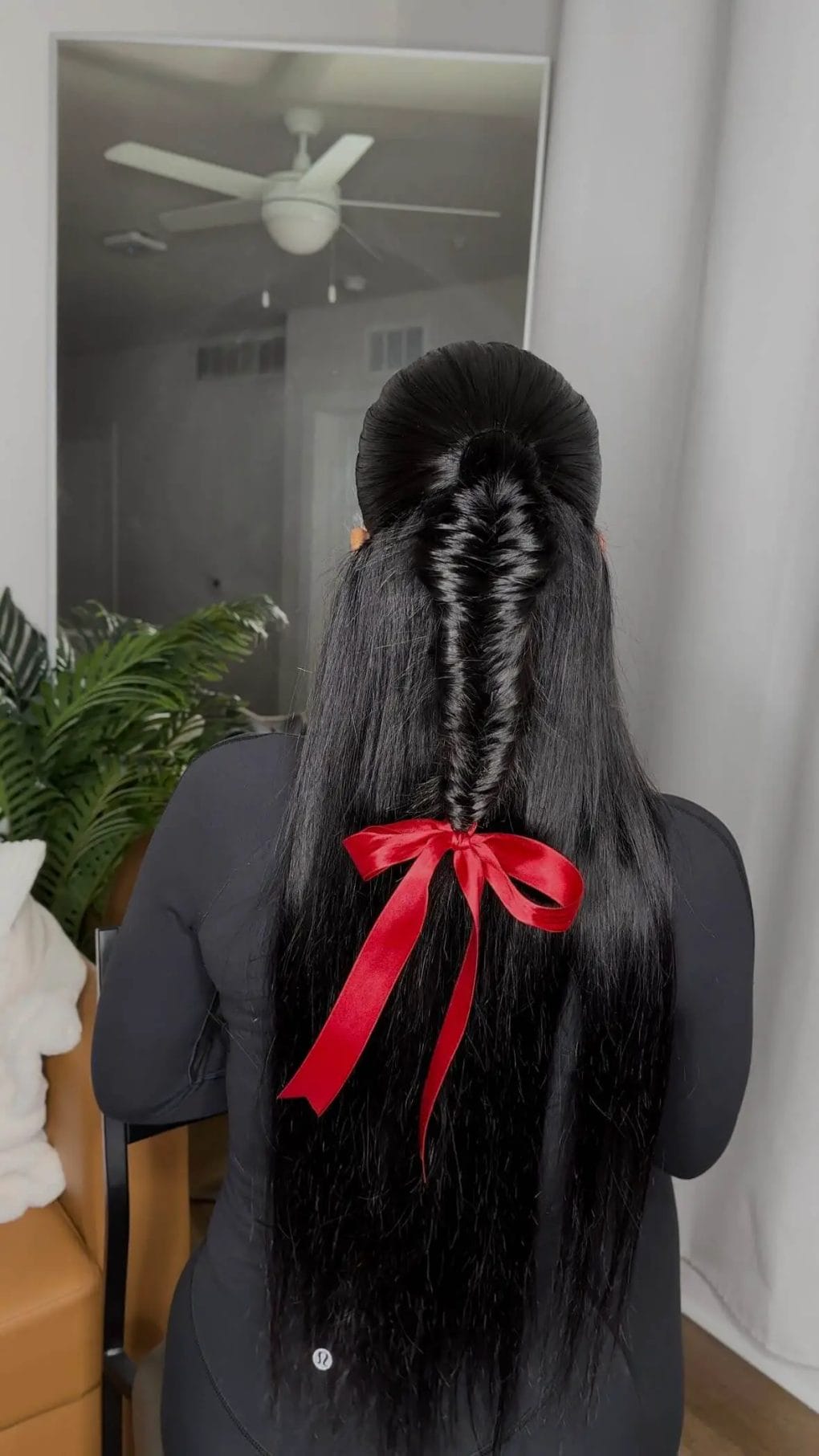 Sleek black hair with a tightly braided detail and red ribbon, adding an edge to a birthday style.