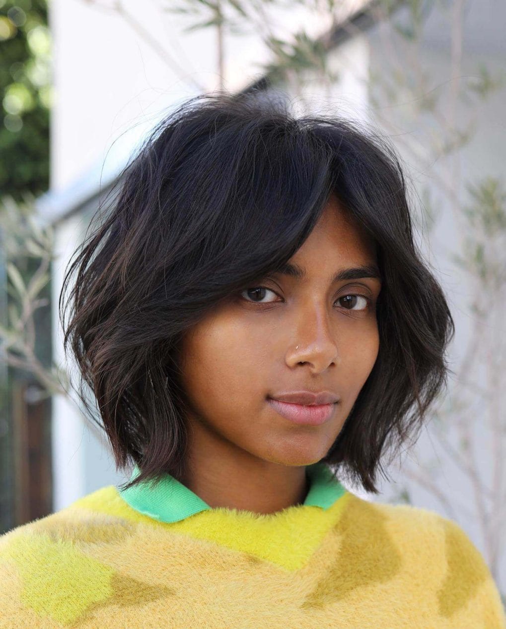 Edgy tousled black bob with softly parted curtain bangs.