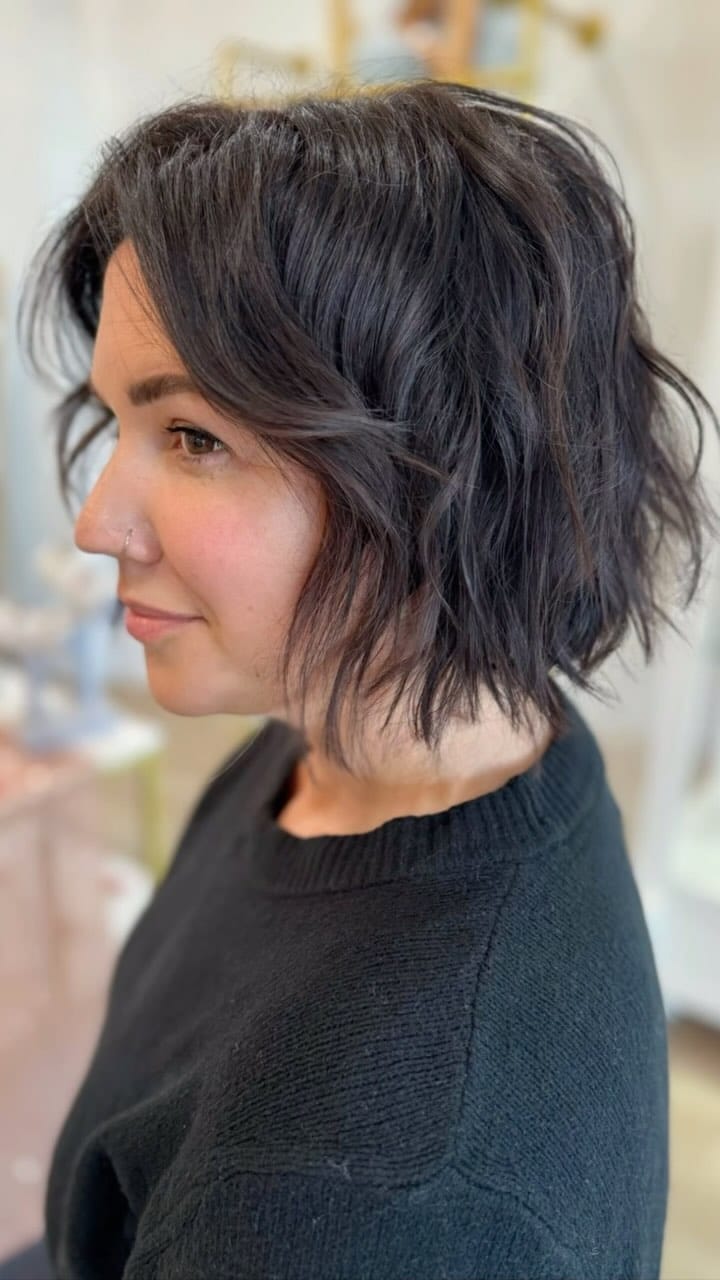 Casual tousled wavy black pixie bob with volume at the roots and face-framing waves