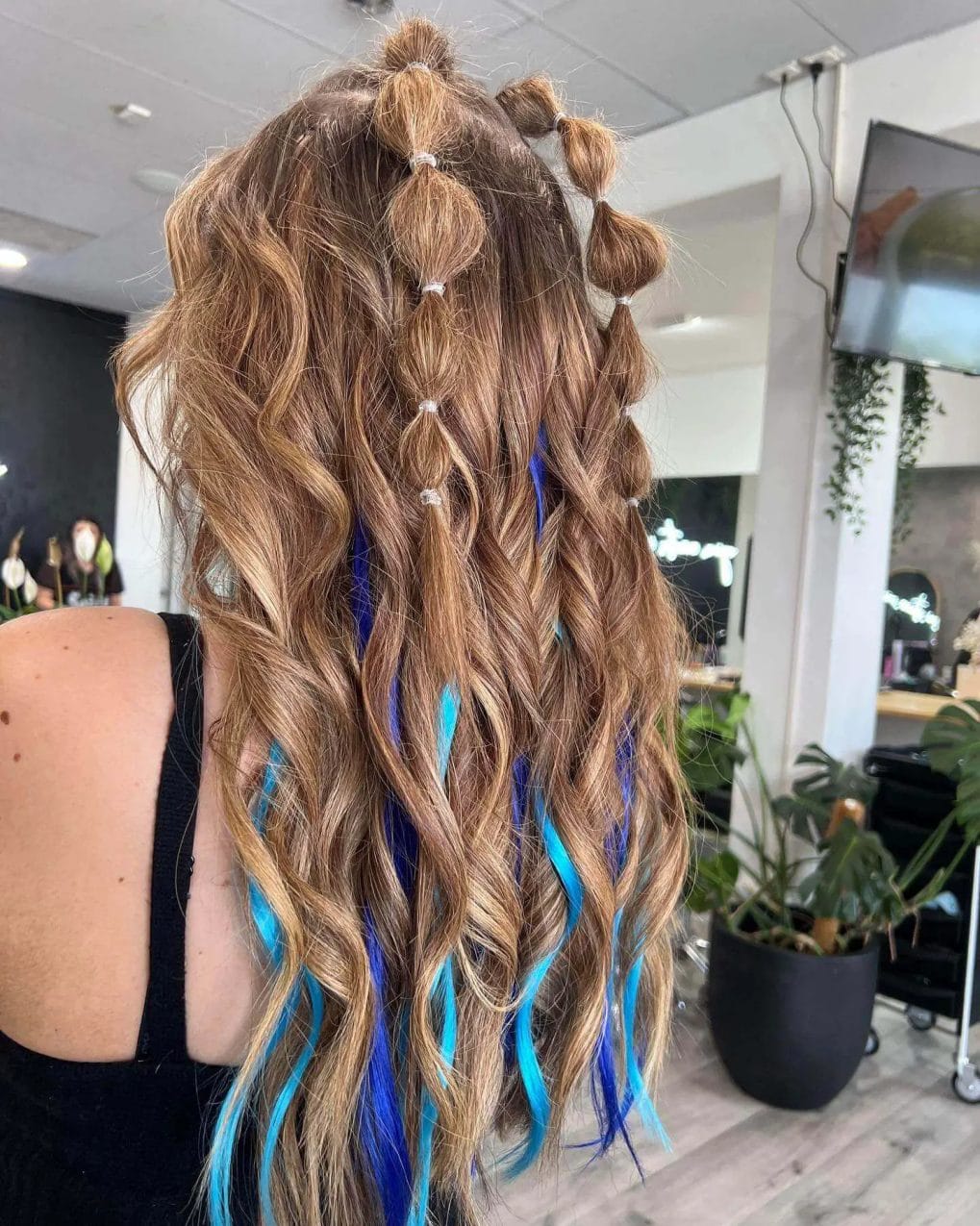 Whimsical buns and beachy waves with bold electric blue extensions, creating a fun, festival-ready hairstyle.