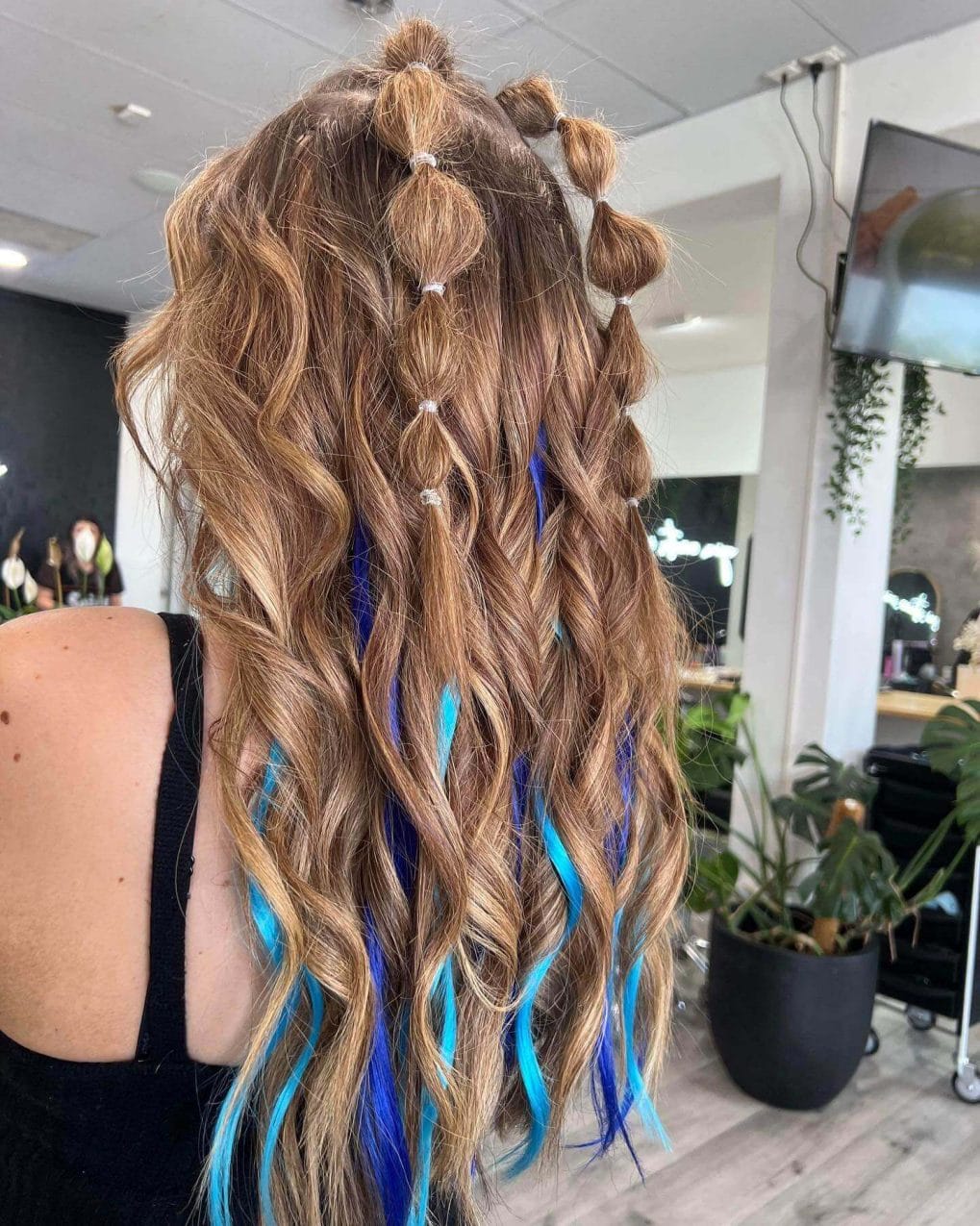 Whimsical buns and beachy waves with bold electric blue extensions, creating a fun, festival-ready hairstyle.