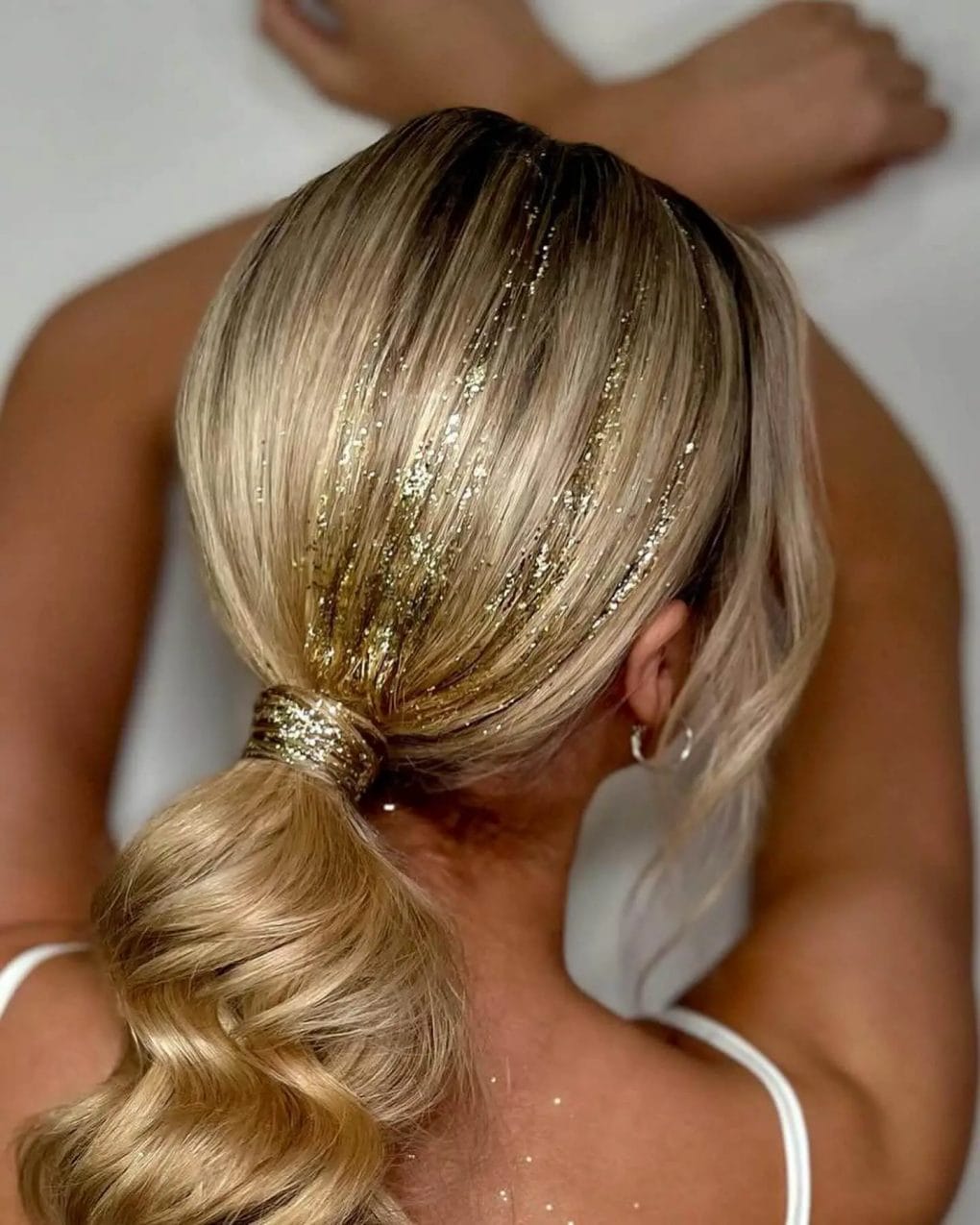 Elegant blonde ponytail with gold glitter strands and voluminous curls for a birthday sparkle.