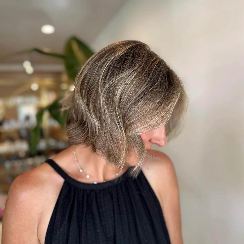 Elegant layered bob with soft curls and cool blonde highlights.