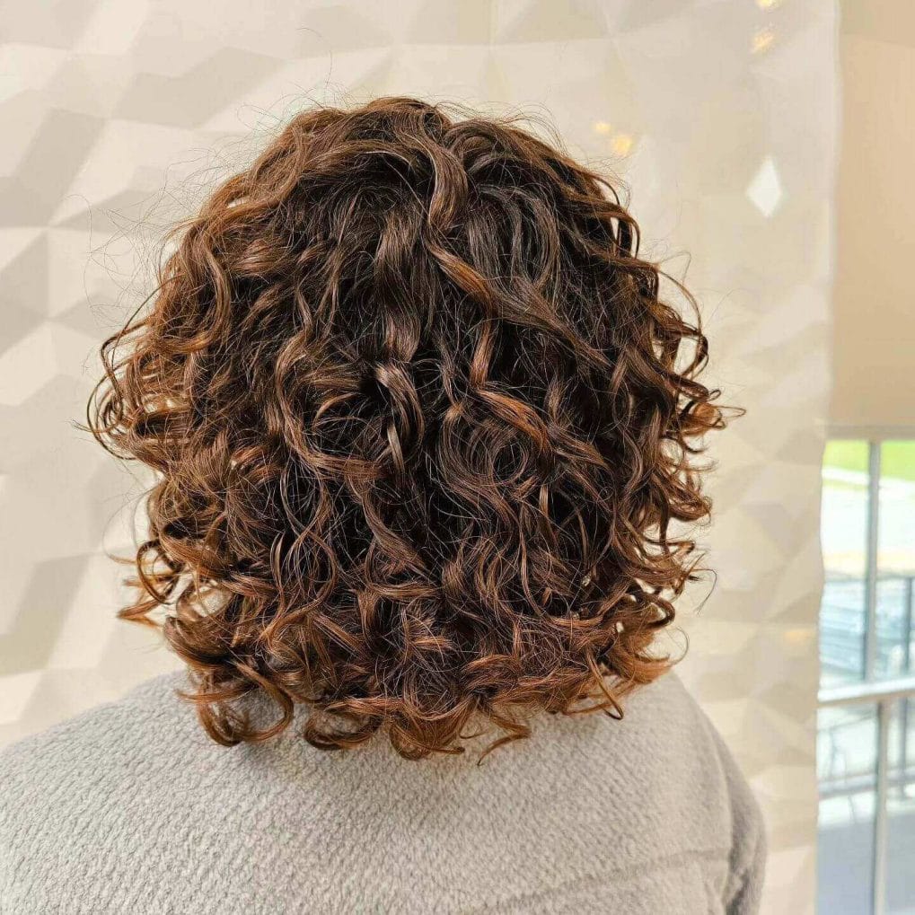 Elegant shoulder-length layers with rich brunette curls.