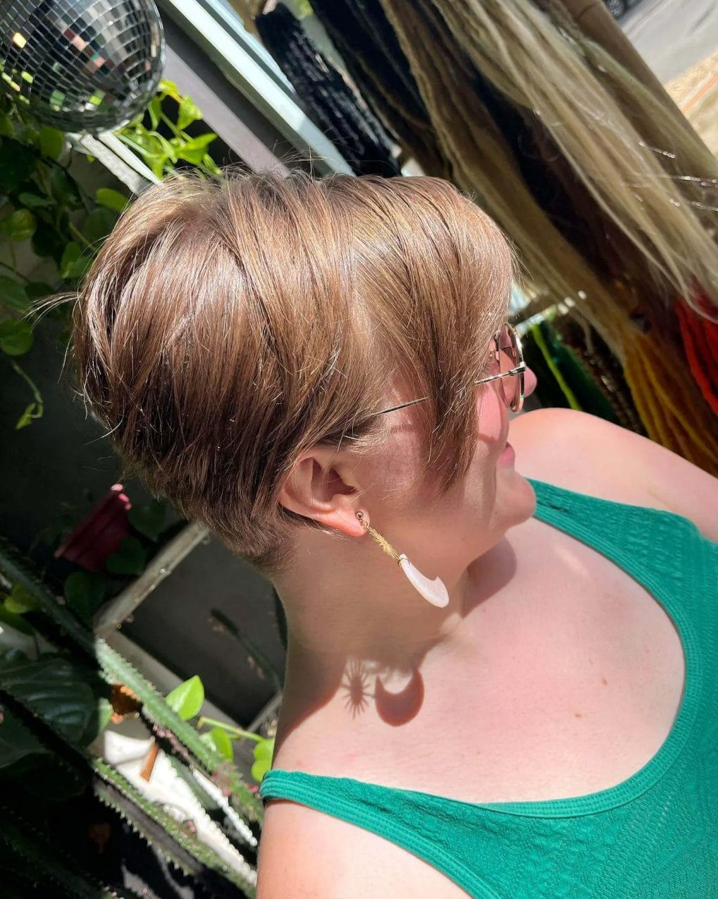Light brown bixie with volume at the crown, tapering to the nape, accompanied by a side-swept fringe.