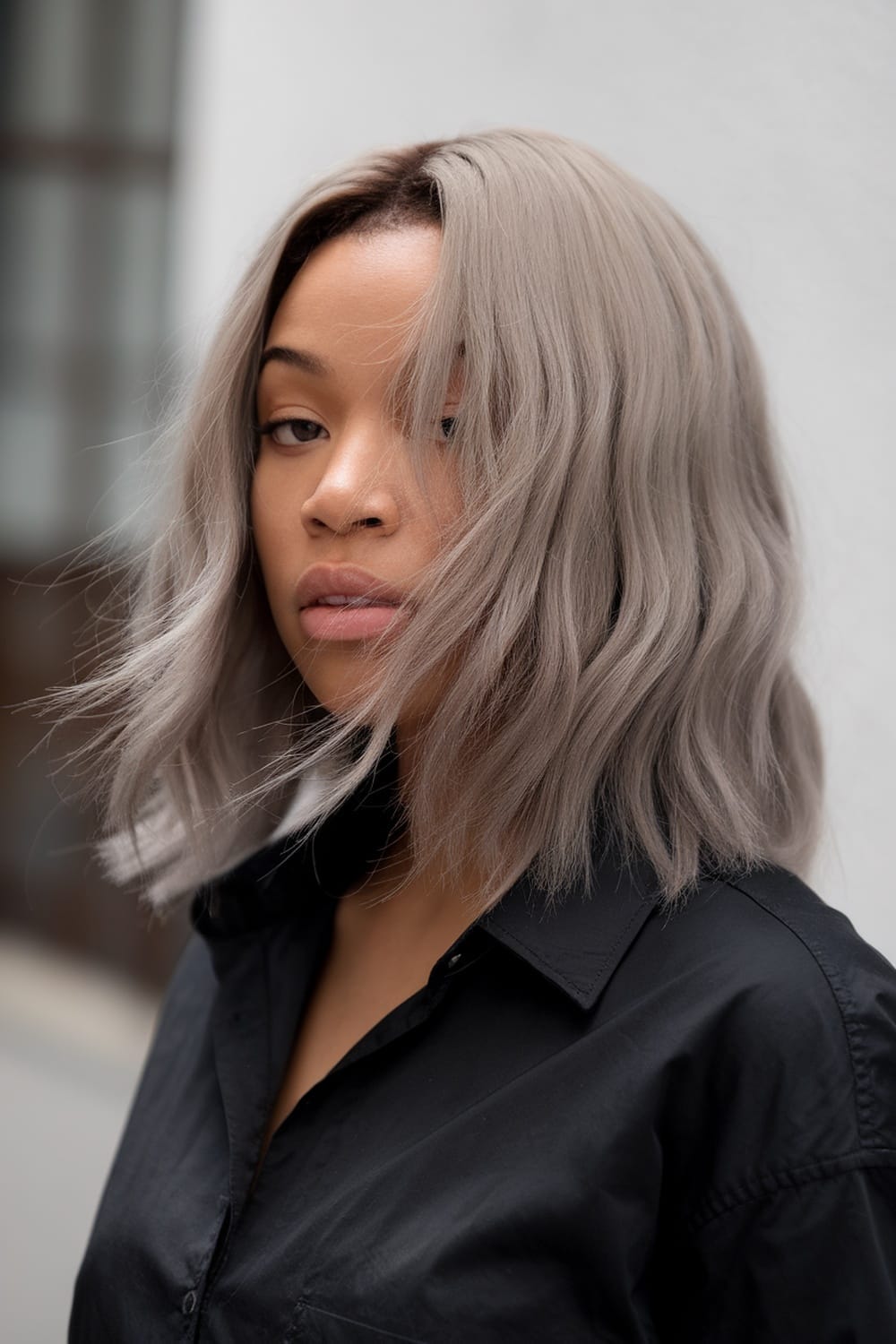 A woman with ash blonde hair styled in soft waves, wearing a black shirt