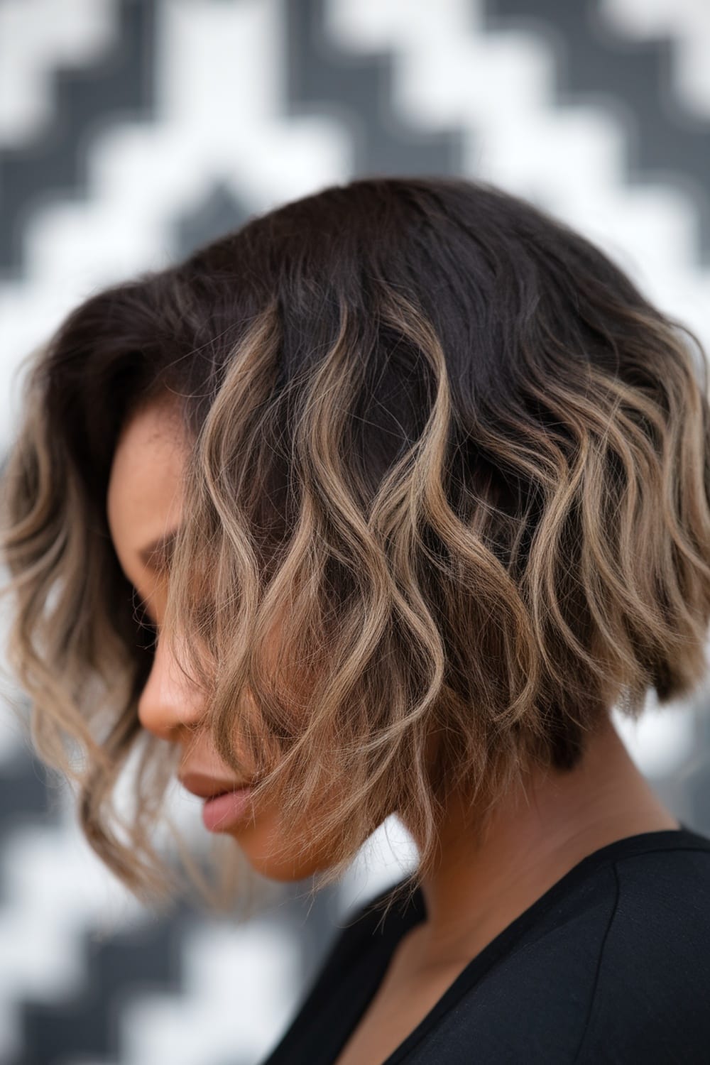 A woman with a textured bob hairstyle, showcasing natural curls and highlights.