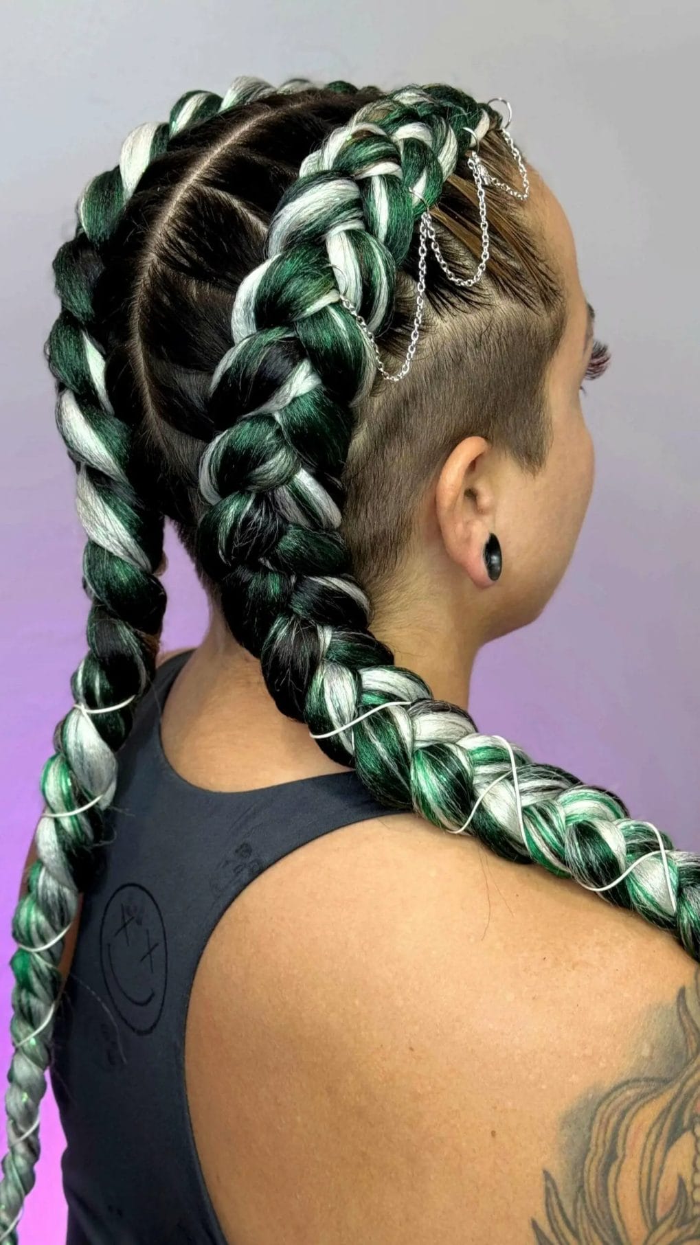 Chunky emerald green and white braids with silver chains and an undercut, blending boldness with festival style.