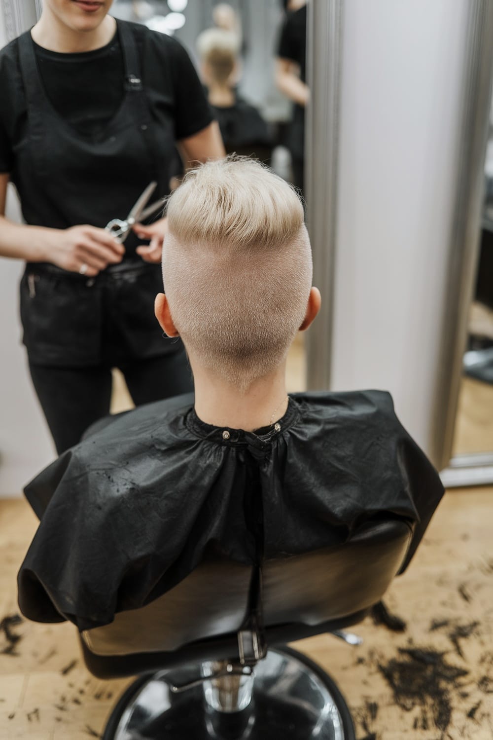 A stylist preparing to cut a client's hair in a salon, showcasing an undercut pixie hairstyle.