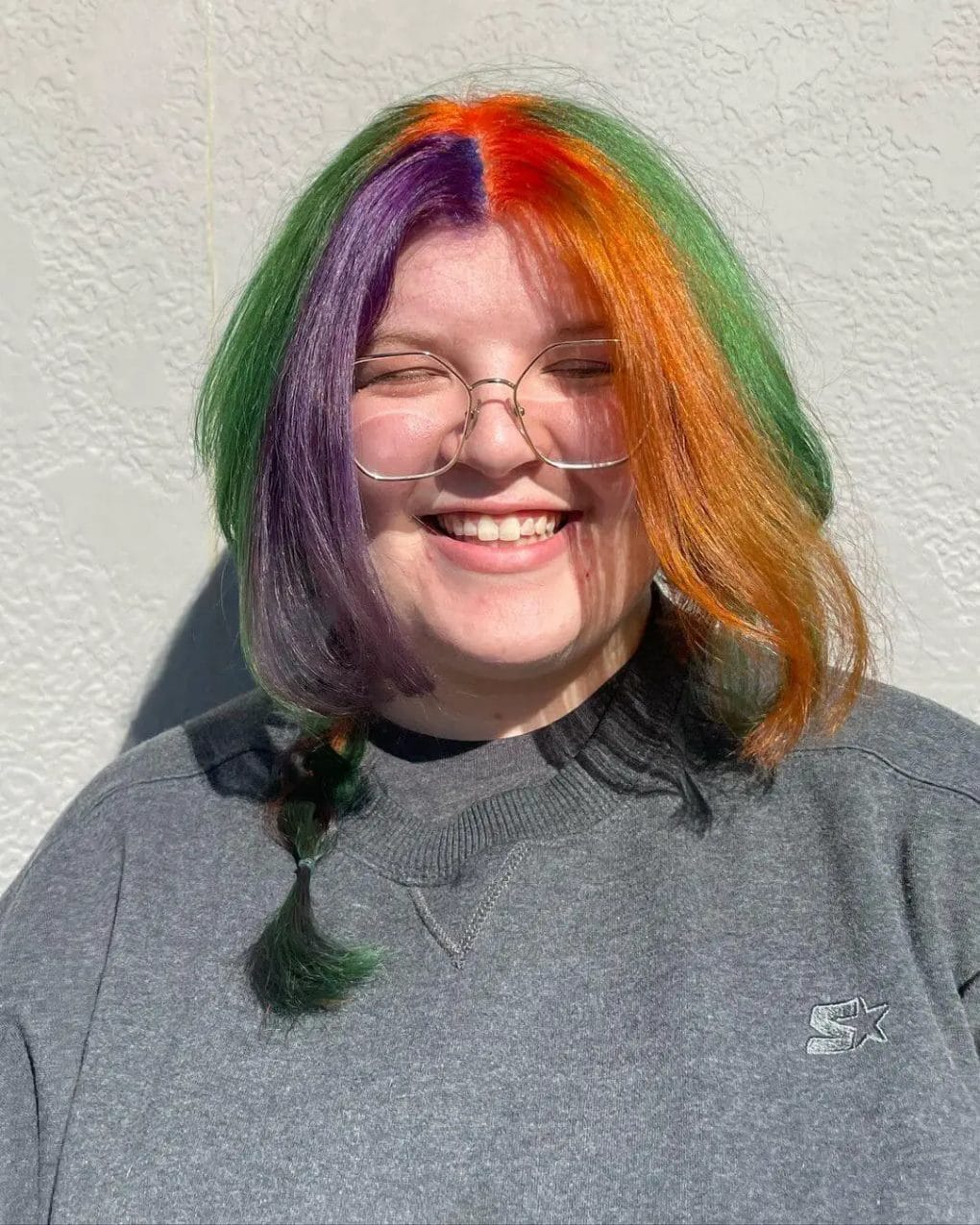 Playful multicolored jellyfish haircut with a mix of orange, purple, and green hues and creative braids.