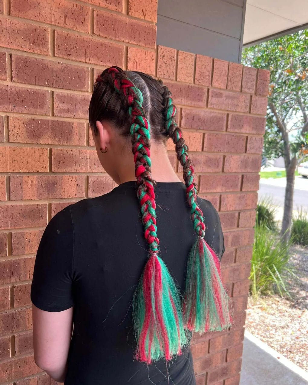 Green and red braids with teal and pink tasseled ends