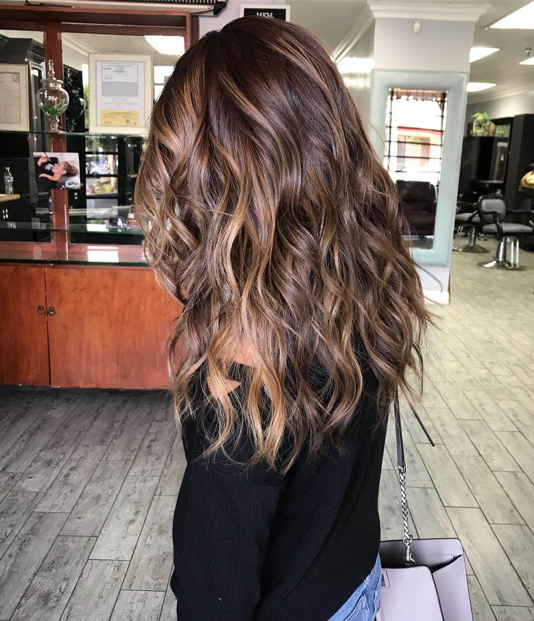 Long layers in chestnut to caramel balayage, echoing the glow of a winter fireplace.