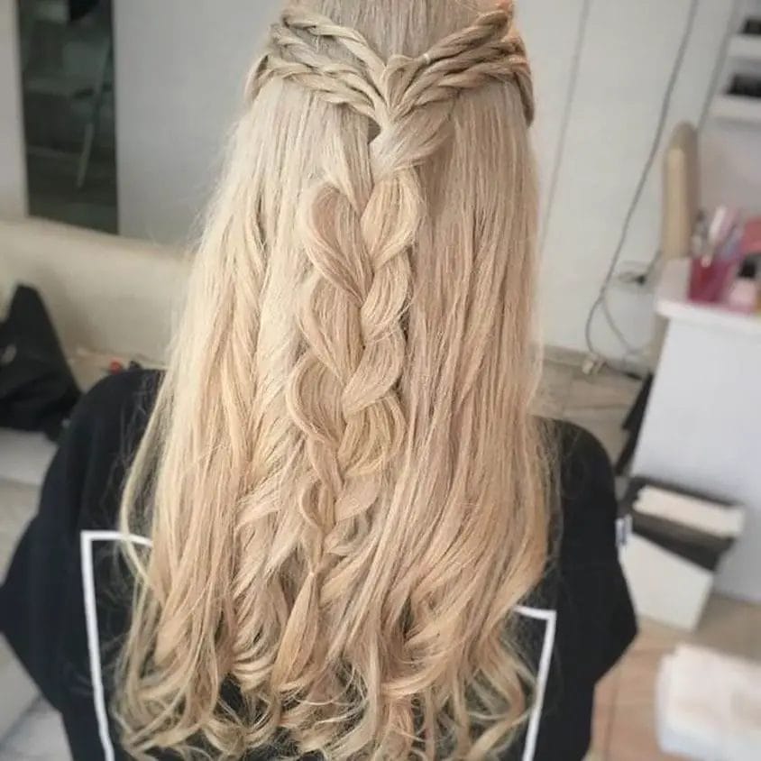 Intricate fishtail braid cascades among blonde wavy hair