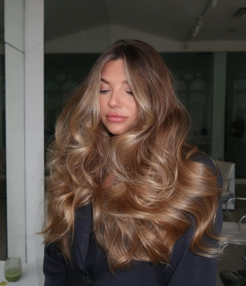 Rich honey-blonde balayage in flowing layers with gentle waves