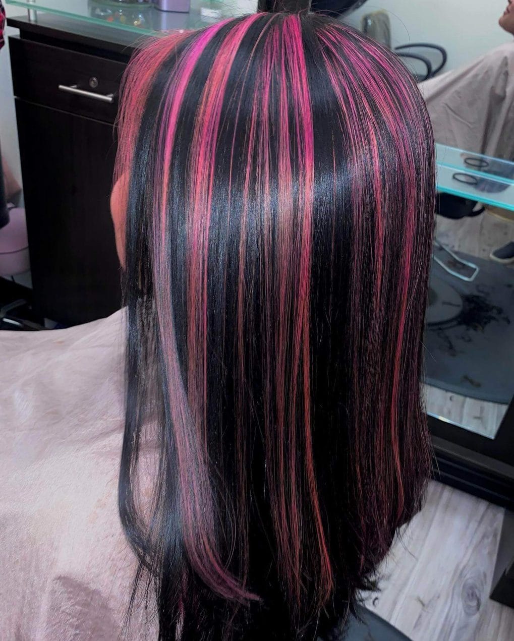 Long hair with soft layers featuring vivid fuchsia chunky highlights on black base.