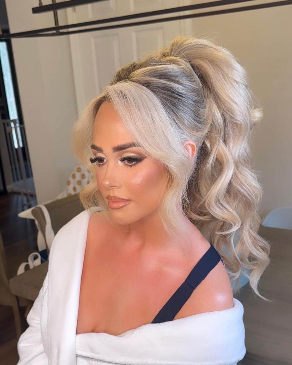 Glamorous ponytail with bouncy ash and platinum blonde curls, accented by romantic side-swept bangs.