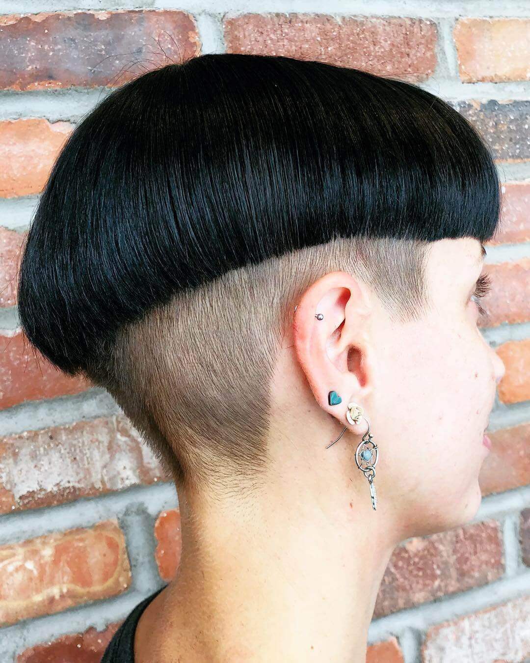 Bold polished mushroom cut with glossy black hair and sharp bangs.